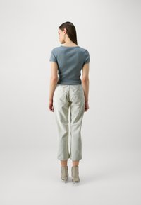 Light blue fitted shirt paired with pale green tapered pants. The outfit features short sleeves and minimalist design with a smooth texture.