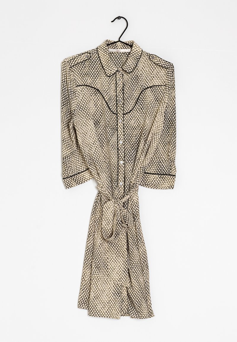 Pitkähihaista mekkoa, joka on valmistettu kevyesti kankaasta ja jossa on musta ja kermainen geometrinen kuvio, napit edessä, kaulus ja vyötärösolki.