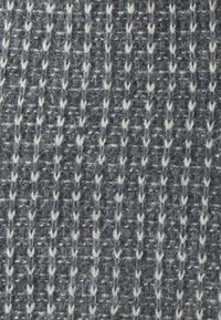 Tumši pelēks adīts audums ar teksturētu rakstu, kurā ir balti ieausti akcenti, veidojot svītrainu dizainu ar dažādas biezuma diegiem.