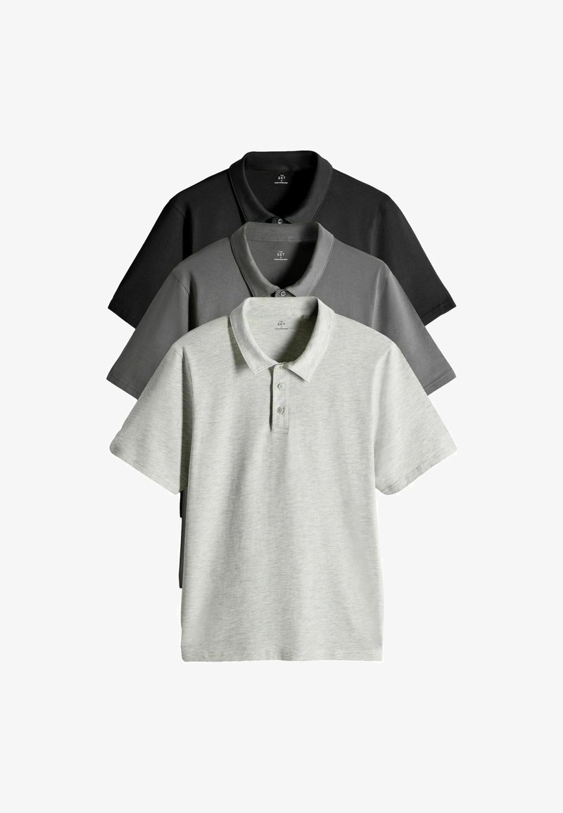 Tři polokošile s krátkým rukávem naskládané na sobě: černá, tmavě šedá a světlě šedá. Každá má límeček, knoflíky a měkkou, hladkou texturu látky.