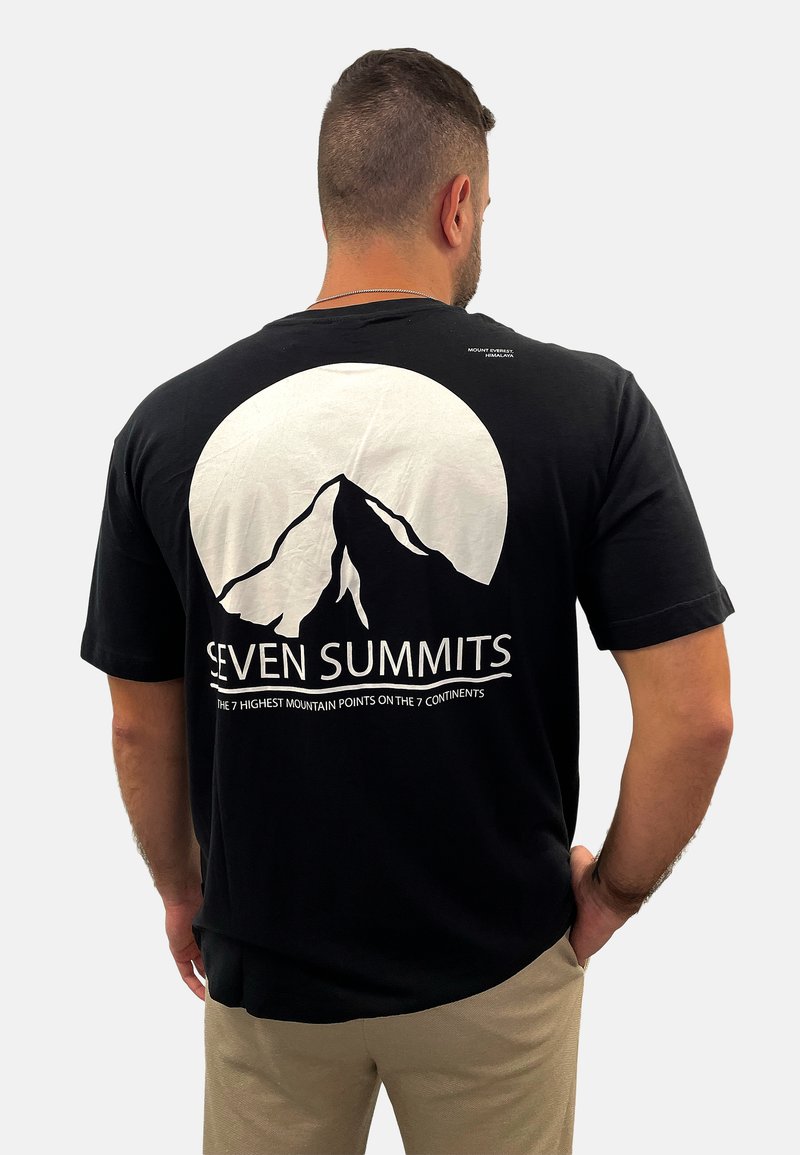 Schwarzes Baumwoll-T-Shirt mit einem weißen Berg-Graphic und dem Schriftzug "SEVEN SUMMITS" auf der Rückseite; mit kurzen Ärmeln und lockerer Passform.
