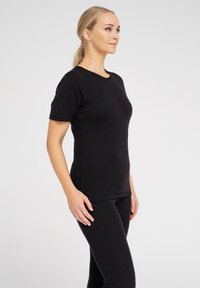 Sort kortærmet tætsiddende t-shirt lavet af ribbet stof, med rund halsudskæring og glat tekstur, parret med matchende sorte leggings.