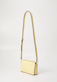 Žuta kožna torbica za crossbody s ravnim pravokutnim oblikom, podesivim remenom i kontrastnim tamnim rubovima. Glatka površina, minimalni hardver.