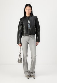 Svart lær cropped jakke med glidelås, som har en ståkrage. Kombinert med lysegrå, flagrende jeans og en metallisk skulderveske.