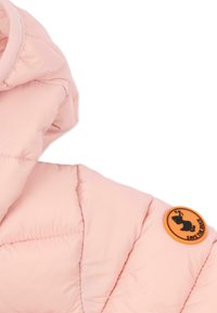 Col de doudoune rose avec une finition texturée et un badge orange circulaire présentant une silhouette noire de canard.