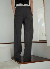 Grijze wijde broek gemaakt van textiel met een gladde tailleband en zijzakken, van achteren getoond tegen een lichte achtergrond.
