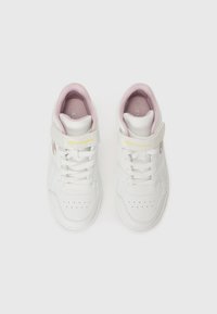 Baskets montantes blanches avec des accents roses, présentant un dessus en synthétique lisse, des perforations pour la respirabilité, et un système de laçage avec une sangle.