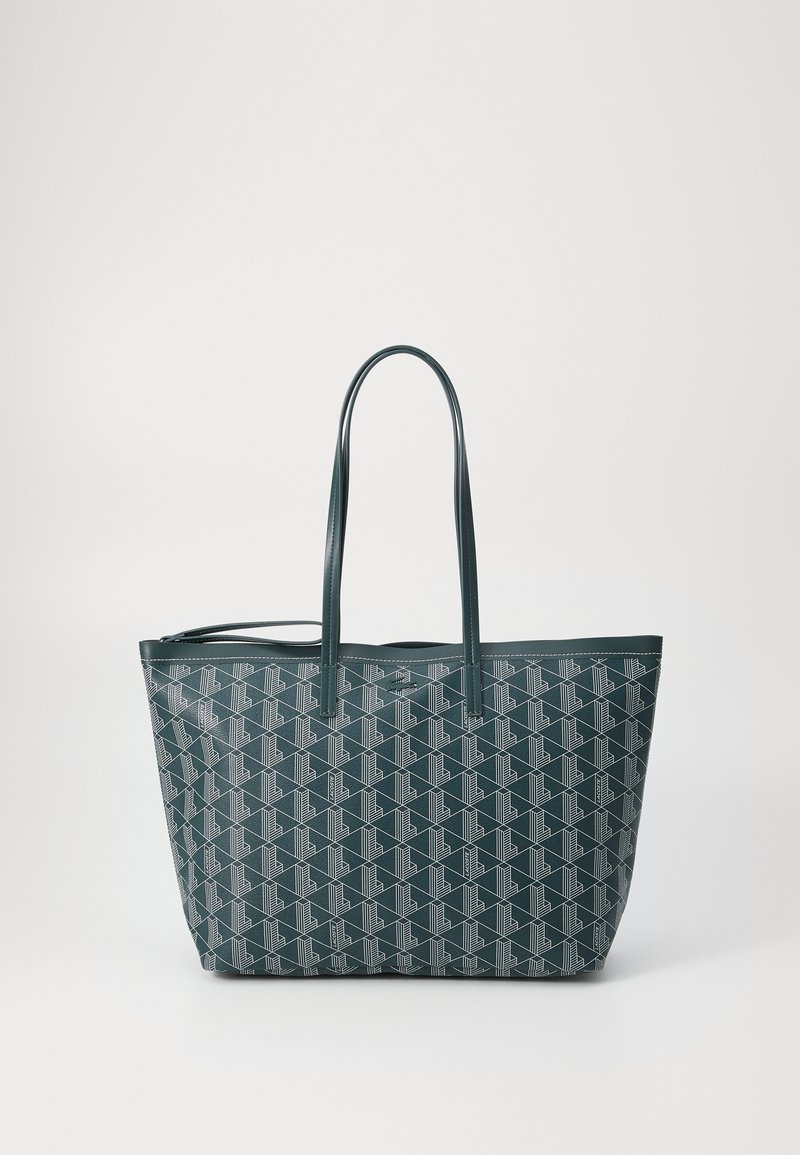 Borsa tote grande in teal scuro, decorata con disegni geometrici bianchi. Realizzata in materiale testurizzato, con due manici robusti e apertura superiore.