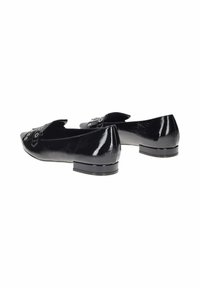 Le ballerine in vernice nera presentano una punta arrotondata, un dettaglio di fibbia decorativa e un tacco basso. La superficie è lucida con una texture sottile.