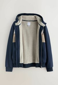 Námornícky modrý zipsový mikina s béžovým fleece podšívkou. Má kapucňu, ribované manžety a pohodlnú vnútornú textúru. Jednoduchý dizajn, žiadne ďalšie vzory.