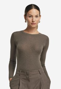 Långärmad ribbad bodysuit i olivgrön, tillverkad av mjukt tyg, med rund halsringning och figurnära silhuett.