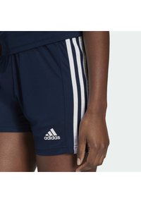 Laivastonsiniset urheilushortsit, joissa valkoiset sivuraidat, kuminauhavyötärö ja valkoinen Adidas-logo helmassa. Sileä kangaspinta.