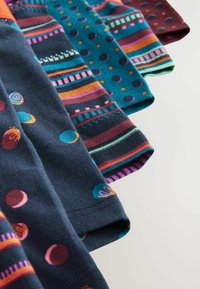 Colección de cinco muestras de tela en varios colores y estampados: azul marino con lunares, rayas y diseños abstractos.