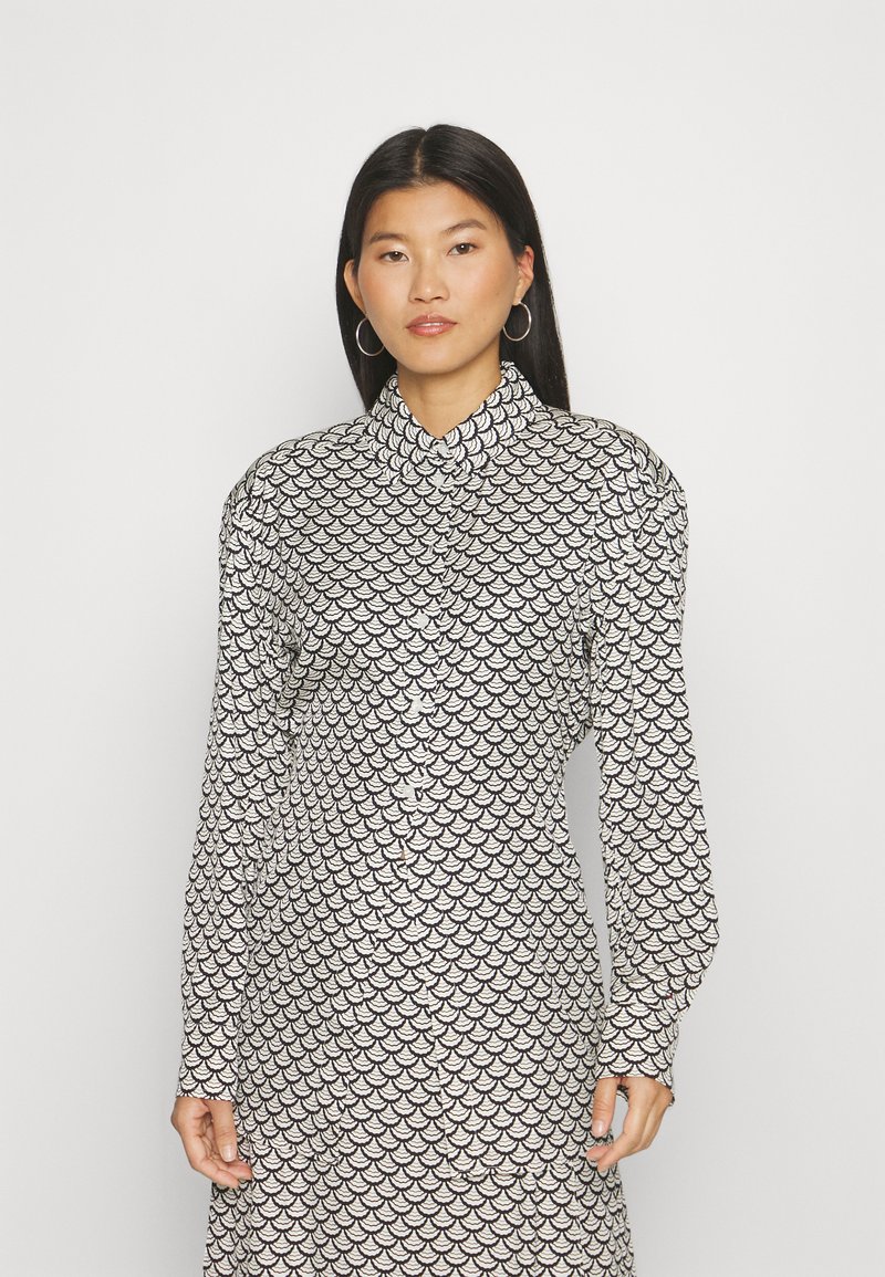 Button-up shirt dress with long sleeves, featuring a black and white scallop pattern, collar design, and a relaxed fit.
