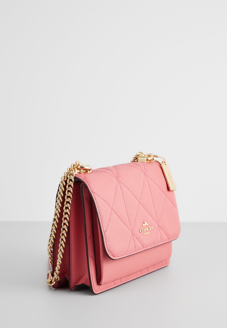 Bolso de hombro de cuero acolchado en color rosa con una correa de cadena dorada, cierre magnético en la solapa y etiqueta con el logotipo. Presenta una textura suave y una forma estructurada.
