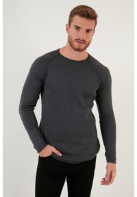 Pulover lung cu mâneci lungi, de culoare gri închis, cu o textură ribbed și decolteu rotund. Dispune de mâneci raglan și o tivă ușor curbată.