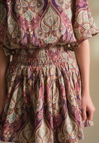 Lilla mustriga kleit, millel on soonikkoeline vöökoht ja paisley-kujundid türkiissinises, oranžis ja valges. Kerge ja voolav kangas.