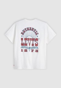 Bjela pamučna majica kratkih rukava. Grafik na leđima prikazuje "Autentični Levi's", crveni i plavi tekst, uz dekorativne zvijezde.