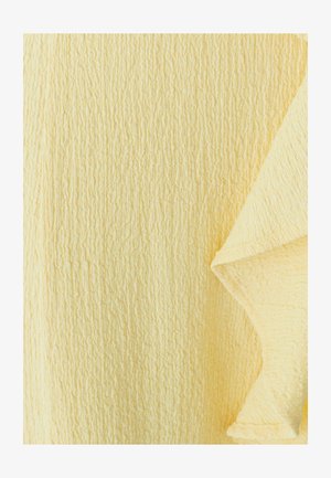 Tekstuuriga kangas pehme pastellkollases toonis voolab elegantselt, rõhutades pindmisi siledusi ja voldikesi.