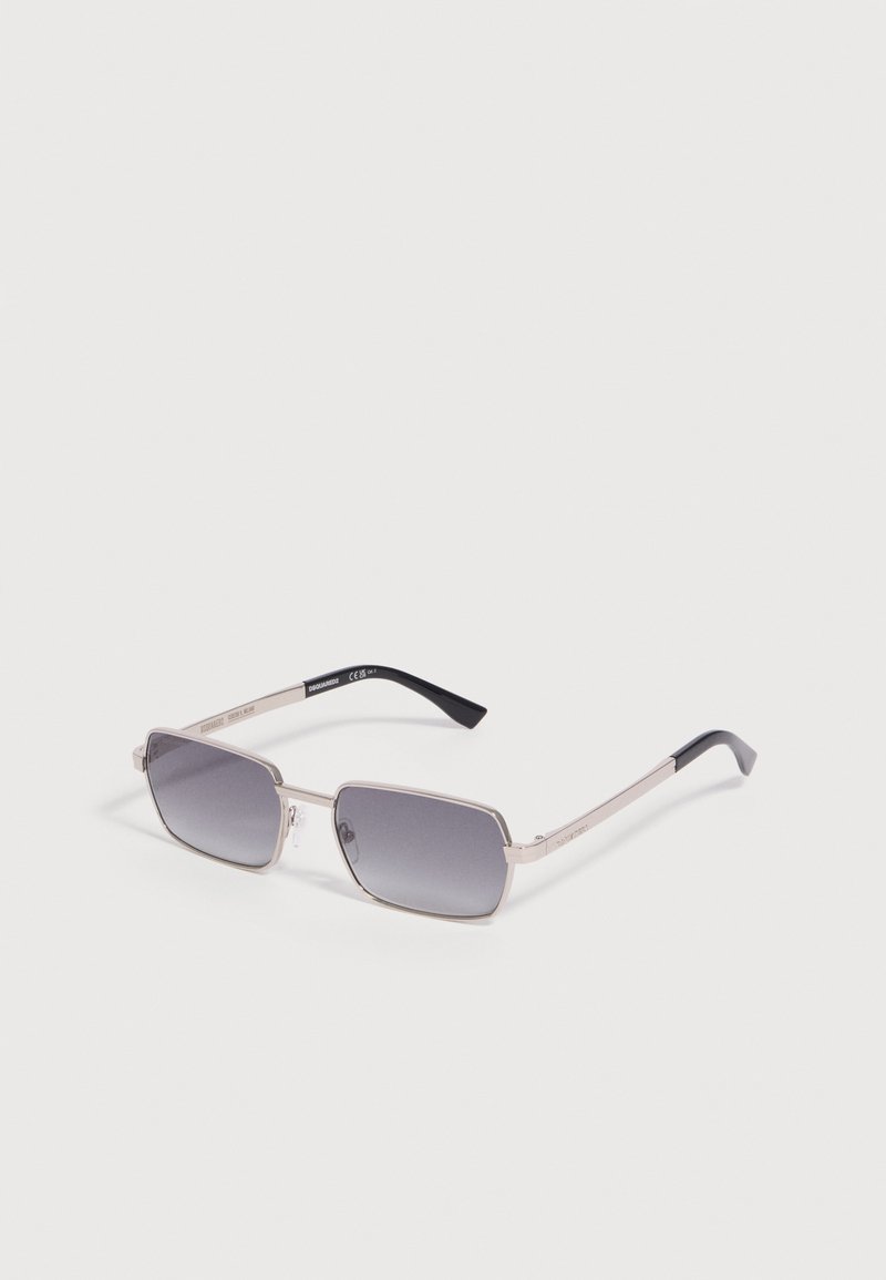 Lunettes de soleil rectangulaires avec montures en métal argenté et verres dégradés foncés, branches avec embouts noirs sur fond blanc uni.