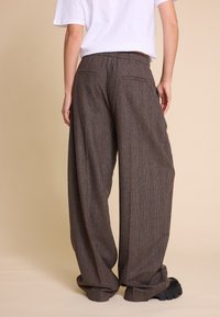 Brune rutete vidde bukser med elastisk midje, to baklommer og et strukturert stoff, kombinert med svarte platåsko.