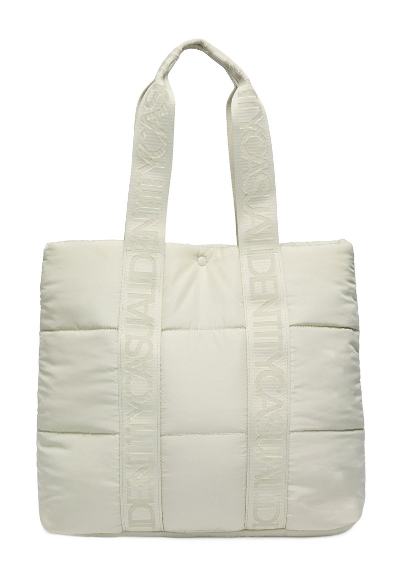 Padded tote bag in light beige fabric with matching reinforced handles. Features a quilted design and embossed logo on handles.