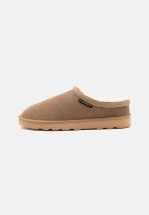 Καφέ παντόφλα τύπου slip-on με μπεζ σόλα και λευκή χνουδωτή επένδυση, πλαϊνή ετικέτα με το λογότυπο Quiksilver, εμφανίζεται σε προφίλ πάνω σε απλό φόντο.