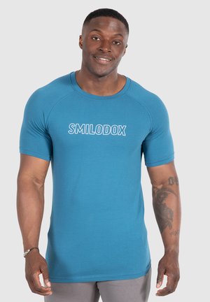 Teal atletisk T-shirt med korte ærmer og rund halsudskæring. Har en hvid "SMILODOX"-logo trykt foran. Blødt, glat stof.
