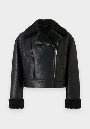 Chaqueta de cuero sintético negra, recortada, con cuello y puños de borrego, cremallera diagonal en el frente y dos bolsillos laterales inclinados.