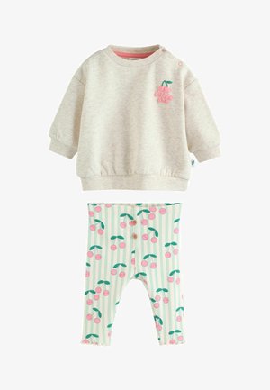 Kermanvärinen vauvan collegepaita, jossa on vaaleanpunainen "Pikkuinen" -kirsikkamerkki, sekä siihen sopivat raidalliset legginssit, joissa on vaaleanpunainen kirsikkakuvio.