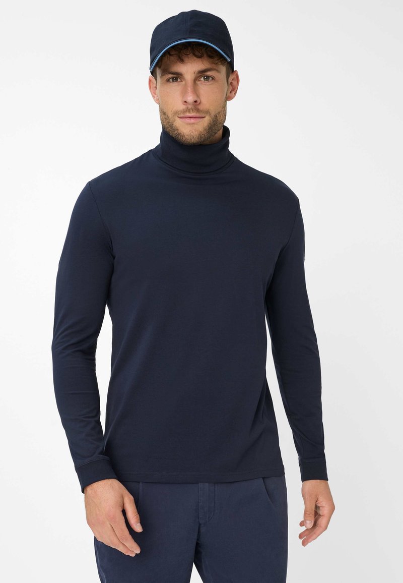 Navyblaues Langarm-Turtleneck-Shirt aus einem weichen, glatten Stoff mit einer figurbetonten Passform, kombiniert mit einer passenden navyblauen Mütze mit einem hellblauen Akzent.