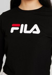 Svart långärmad skjorta i bomull med rund halsringning. Funktioner en framträdande vit "FILA"-logotyp med röda accenter.