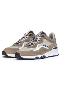 Brązowe zamszowe i siateczkowe trampki o warstwowym designie z białymi akcentami, szarymi sznurowadłami i teksturowaną podeszwą. Charakterystyczny ząbkowany wzór podeszwy.