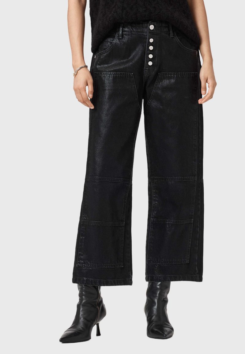 Pantaloni larghi neri realizzati in un materiale lucido, con vita alta, tasche frontali e cinque bottoni argentati lungo il davanti.