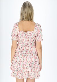 Blumendruckkleid in Hellrosa mit Puffärmeln, gerafftem Oberteil und gestuftem Rüschensrock. Verfügt über kleine, mehrfarbige Blumen.