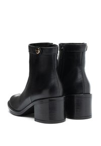 Stivaletti neri in pelle con tacco a blocco, chiusura con zip e un dettagli decorativo in oro nella parte superiore del gambale.