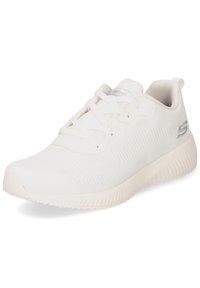 Sneaker sportivo bianco con tomaia in tessuto testurizzato, punta arrotondata e suola in gomma a contrasto. Presenta lacci e un accento del logo argentato.
