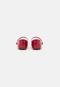 Punaiset lakatut nahkaiset slingback-kengät, joissa on matala korko, sileä pinta ja minimalistinen muotoilu. Varustettu säädettävillä nilkkaremmillä ja suljetulla takaosa.