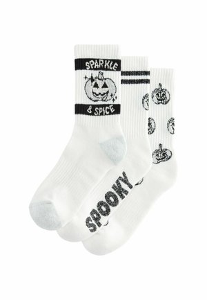 Tre par vita strumpor med svarta mönster: ett par med "SPOOKY", ett annat med en pumpagrafik, och ett randigt band. Mjuk textur.