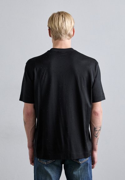 Svart t-skjorte med korte ermer og et teksturert mønster, med små, spredte detaljer. Laget av lett stoff, med en klassisk rund hals.