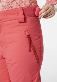 Rosa snöbyxor med en slät textur, en ficka med dragkedja och justerbart kardborreband i midjan för en säker passform.