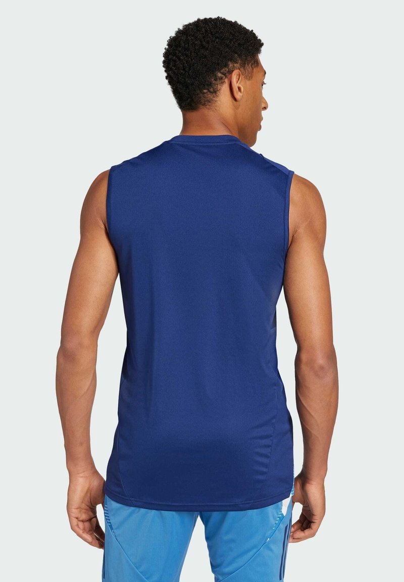 Camiseta deportiva sin mangas de color marino con escote redondo, textura suave y ligeras aberturas laterales para mayor movilidad. Vista trasera que muestra el diseño de los hombros.