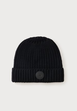 Bonnet noir tricoté avec une texture côtelée et un logo rond sur patch cousu sur le revers, présenté sur un fond blanc.