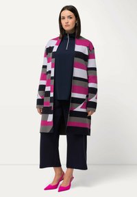 Randig kofta i rosa, grått och svart, öppen fram, kombinerad med en mörk topp, vida byxor och rosa spetsiga klackar. Platt textur.