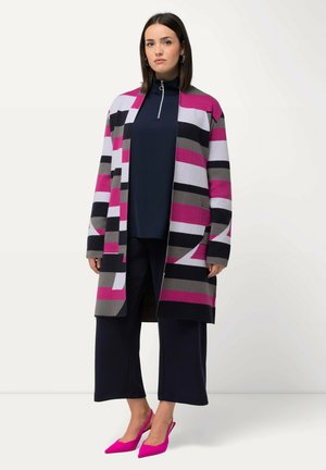 Cardigan rayé rose, gris et noir, à l'avant ouvert, associé à un haut sombre, un pantalon large et des escarpins pointus roses. Texture lisse.