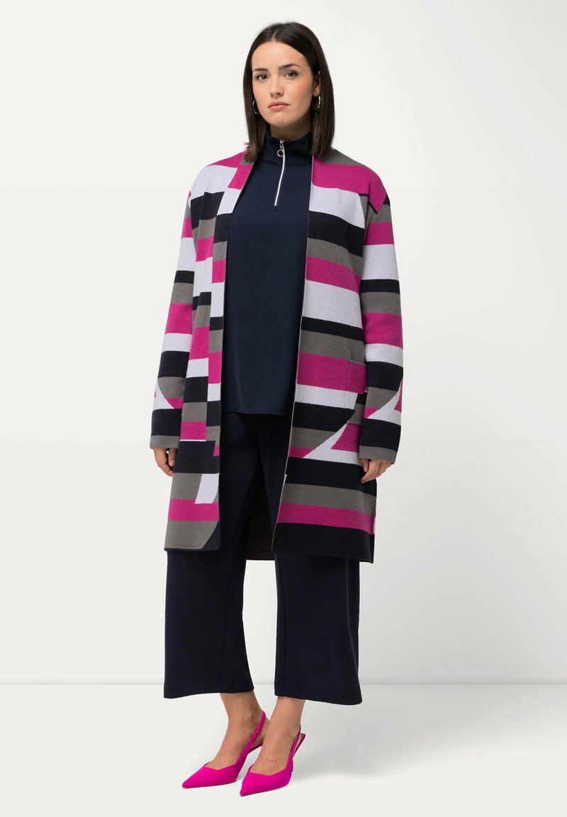 Randig kofta i rosa, grått och svart, öppen fram, kombinerad med en mörk topp, vida byxor och rosa spetsiga klackar. Platt textur.