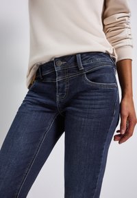 Mörkblå denimjeans med slim fit, med medelhög midja, klassisk femfickdesign och kontrasterande sömmar.