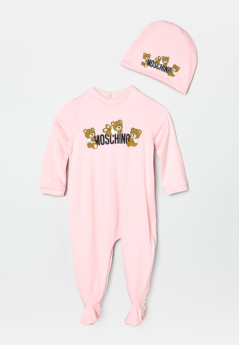 Un grenouillère en coton rose à manches longues, ornée de graphiques d'ours et du texte "Moschino". Comprend un bonnet en tricot rose assorti avec un motif d'ours.