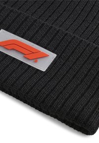 Czarna, prążkowana czapka beanie z fakturowanym wykończeniem, z prostokątną białą metką z czerwonym logo i zaokrąglonymi rogami.