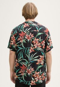 Maglietta nera a maniche corte con un vivace motivo floreale in arancione e rosa. Presenta foglie verdi e una vestibilità comoda. Tessuto morbido.